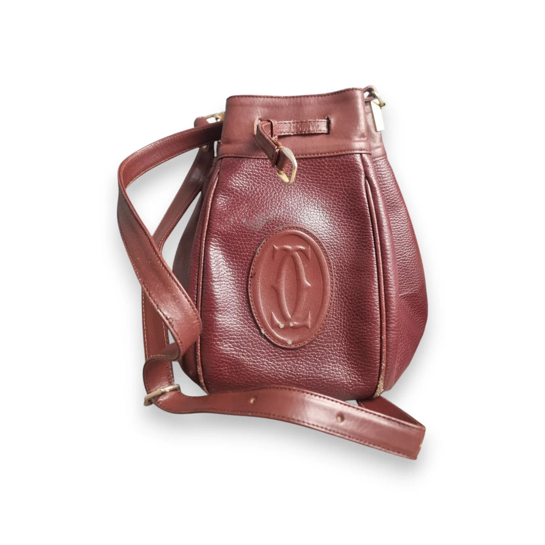 Borsa a secchiello vintage Must de Cartier in pelle bordeaux vista frontale con tracolla.