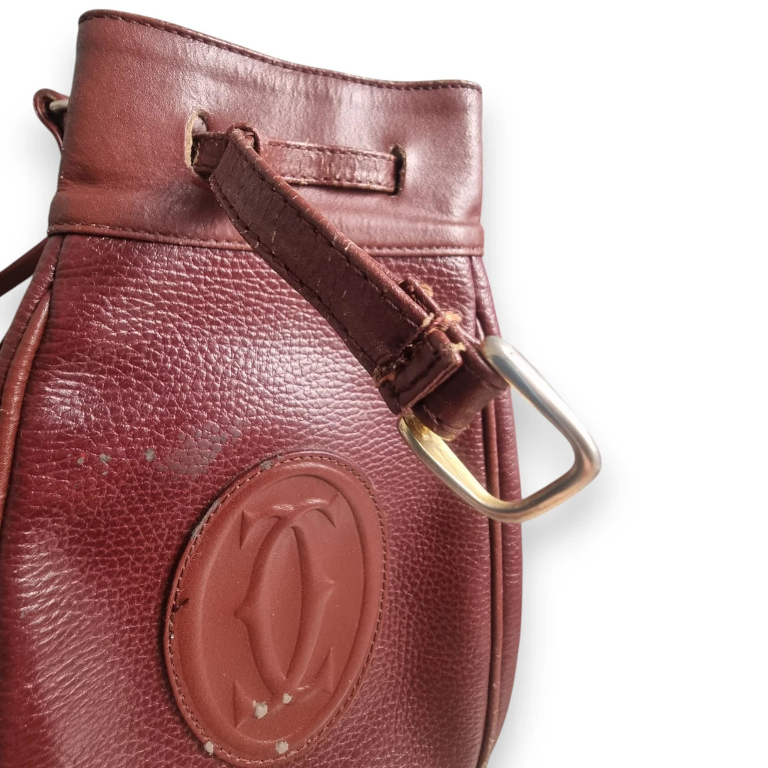 Dettaglio del passante di chiusura e dei graffi superficiali su pelle Cartier bordeaux.