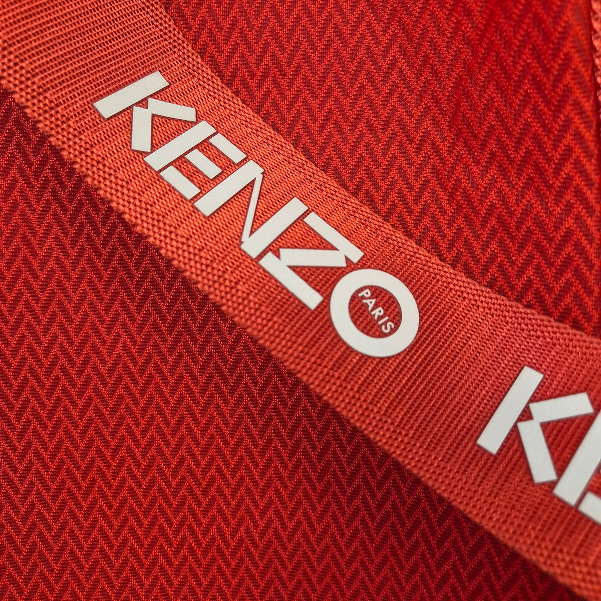 Dettaglio ravvicinato del logo Kenzo Paris bianco stampato sulla tracolla in nastro rosso.