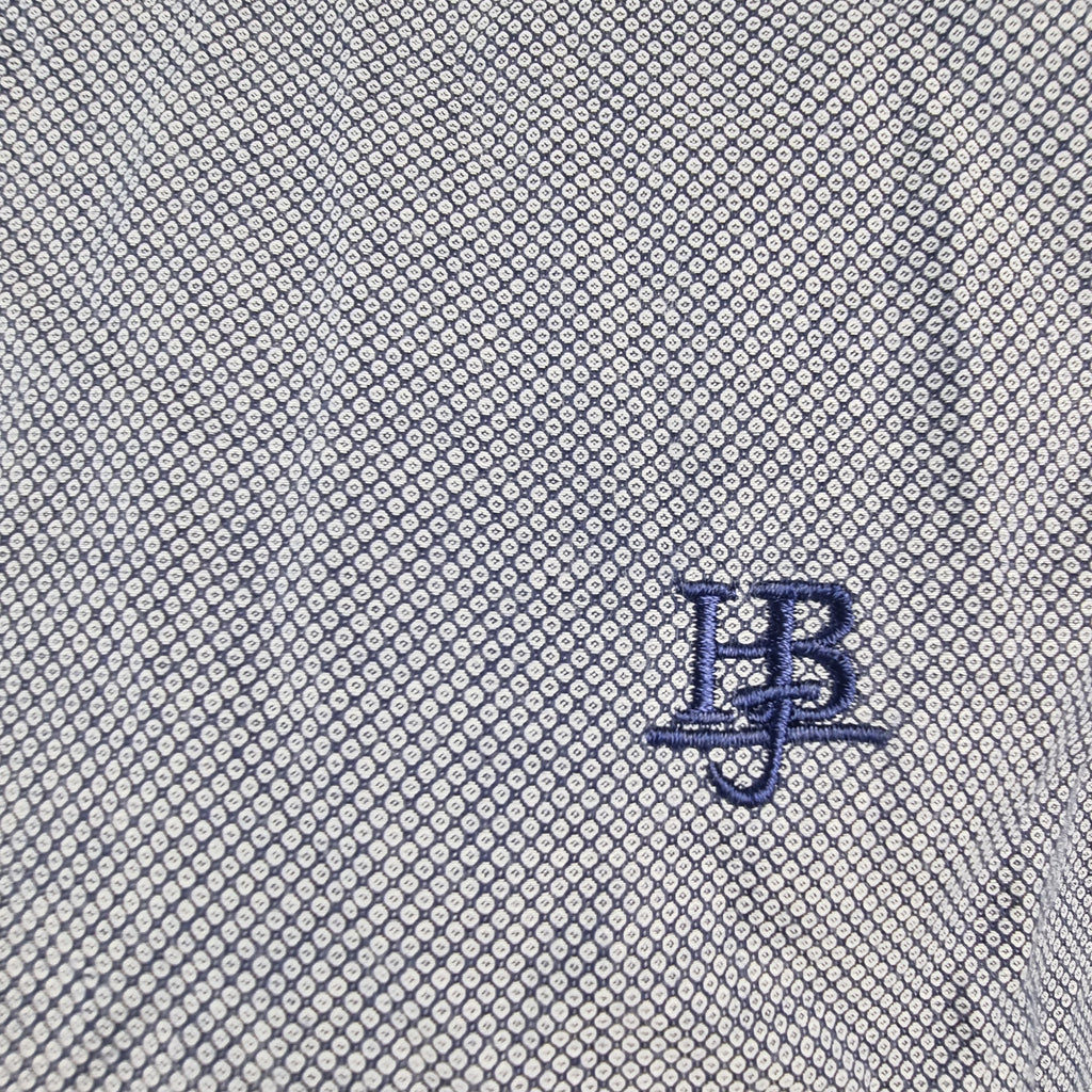 Dettaglio ravvicinato del monogramma HB ricamato sul tessuto a micro pattern.