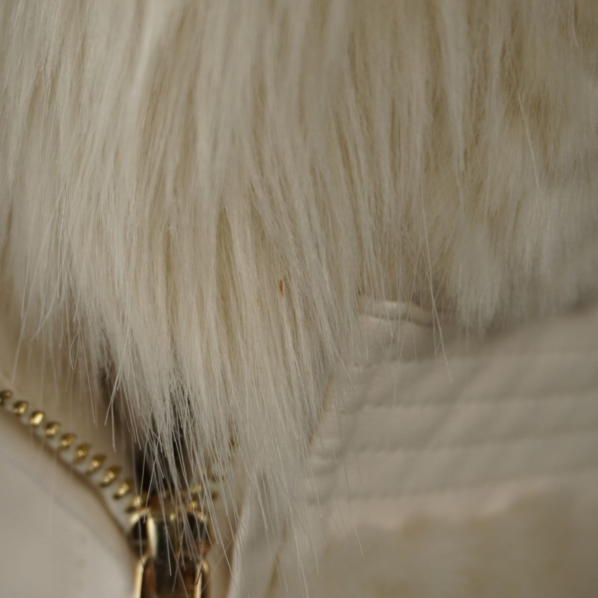 Dettaglio ravvicinato della pelliccia bianca e della cerniera del gilet Guess.