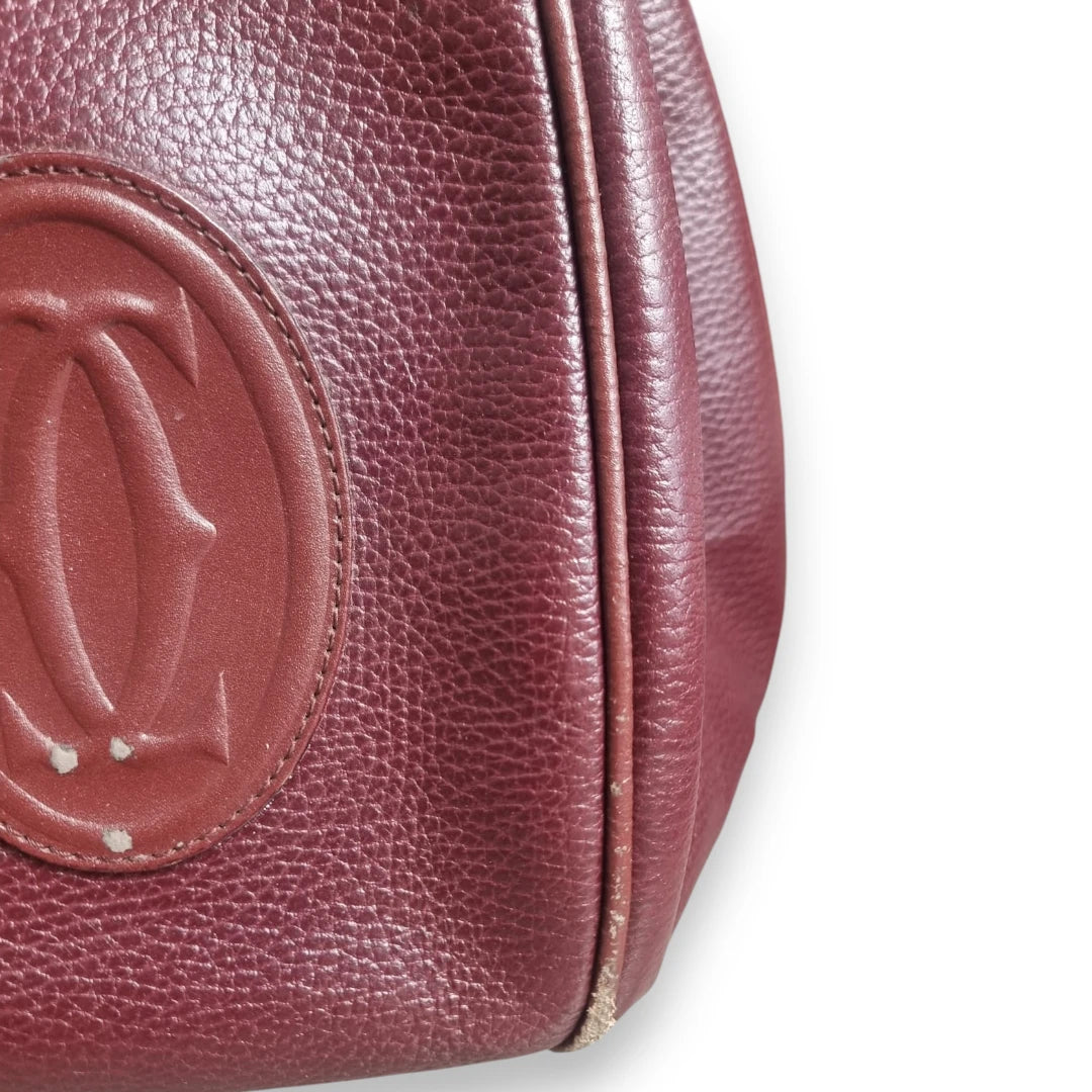  Dettaglio usura del bordo inferiore e della pelle di una borsa Cartier vintage bordeaux.