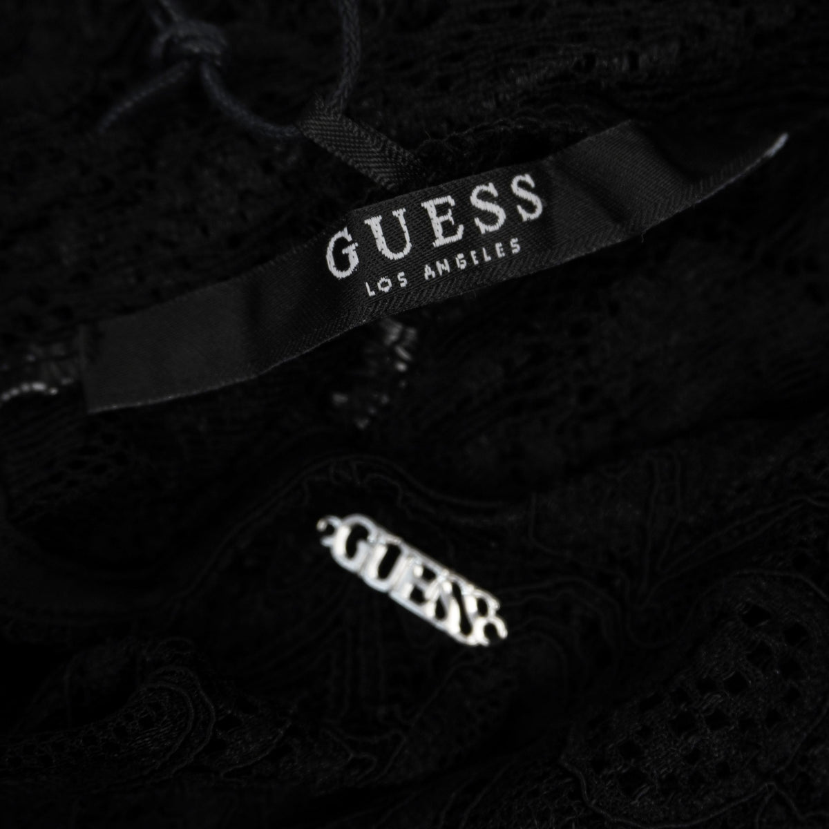 Etichetta interna in tessuto nero con marchio Guess Los Angeles.