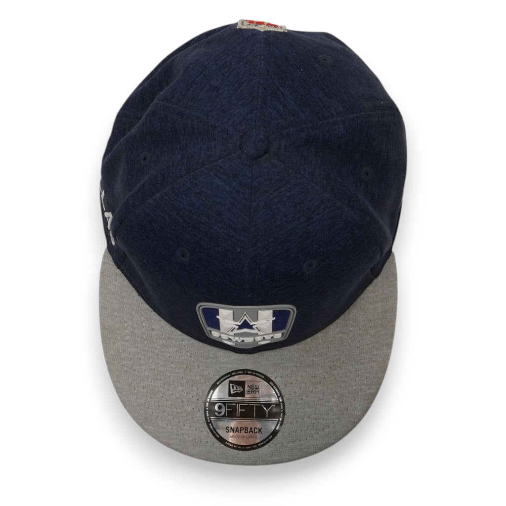 Inquadratura dall'alto del cappello blu con visiera grigia e adesivo argentato rotondo 9FIFTY.