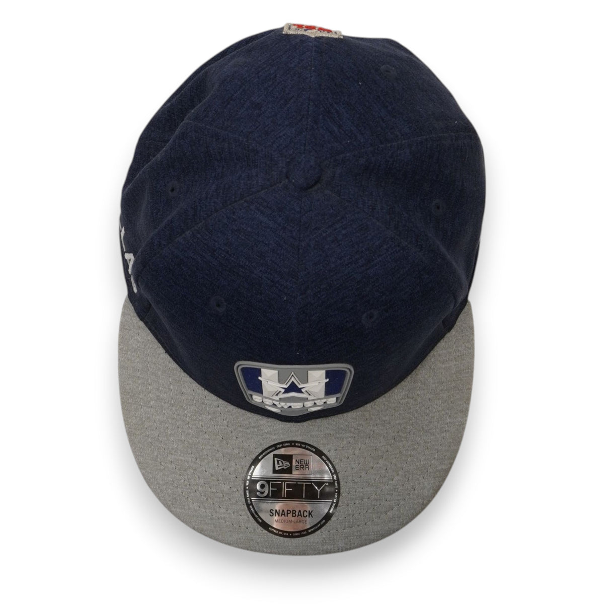 Inquadratura dall'alto del cappello blu con visiera grigia e adesivo argentato rotondo 9FIFTY.