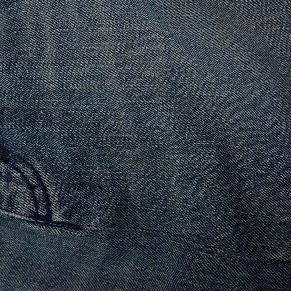 Inquadratura macro del tessuto denim che mostra una lieve macchia superficiale.