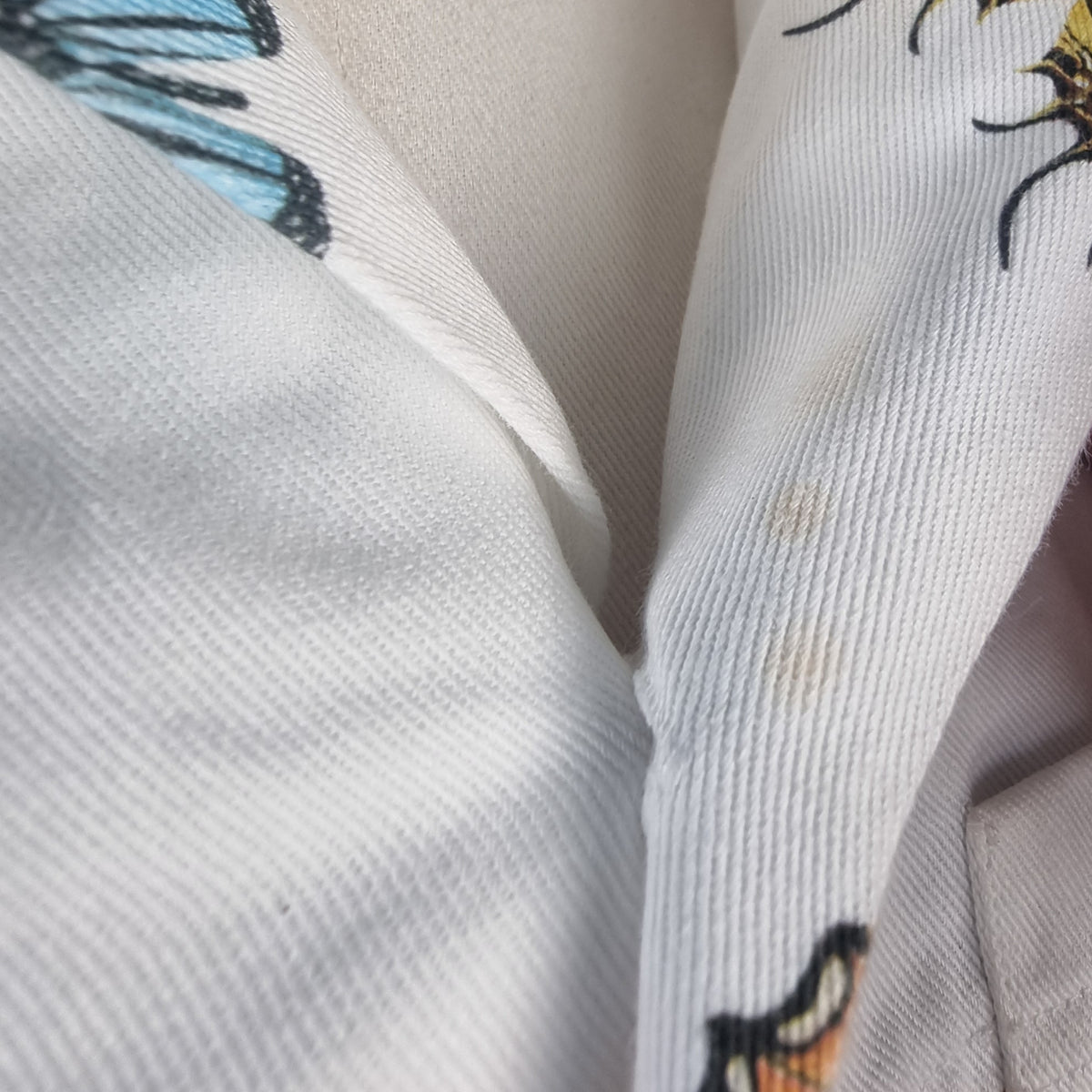 Inquadratura ravvicinata di due piccoli aloni sul tessuto in denim bianco della giacca.