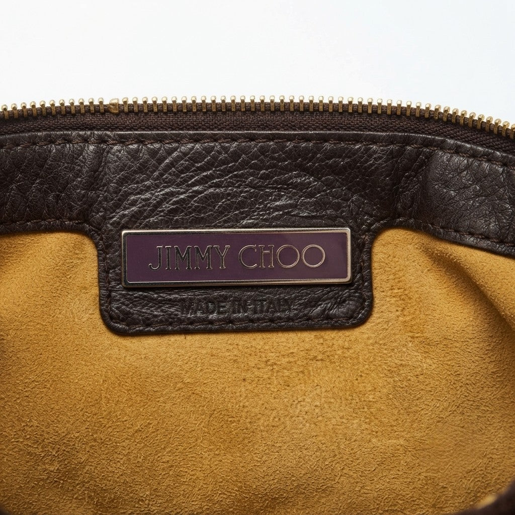 Interno della borsa con targhetta metallica viola Jimmy Choo e scritta Made in Italy sulla pelle.