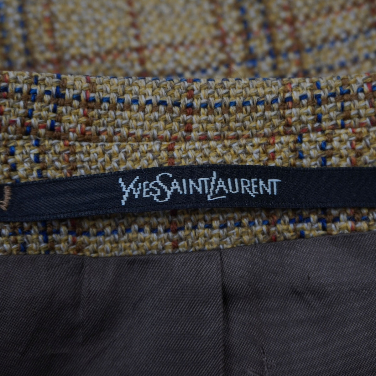 Particolare del nastro con marchio Yves Saint Laurent sul bordo interno del colletto.