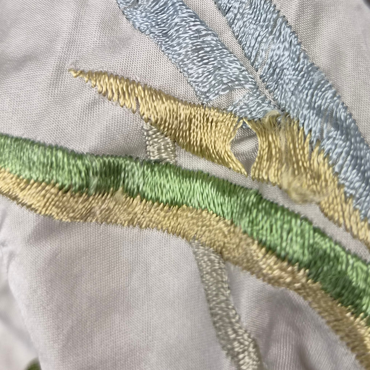  Particolare del ricamo verde e giallo che mostra fili leggermente logorati.