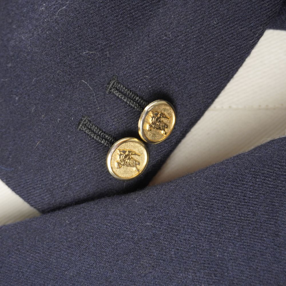 Particolare della manica del blazer blu con due bottoni dorati decorativi sui polsini.