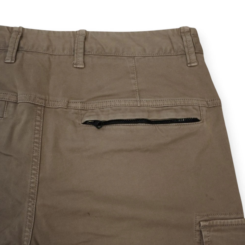 Particolare della tasca posteriore destra dei pantaloni cargo con chiusura a cerniera nera.
