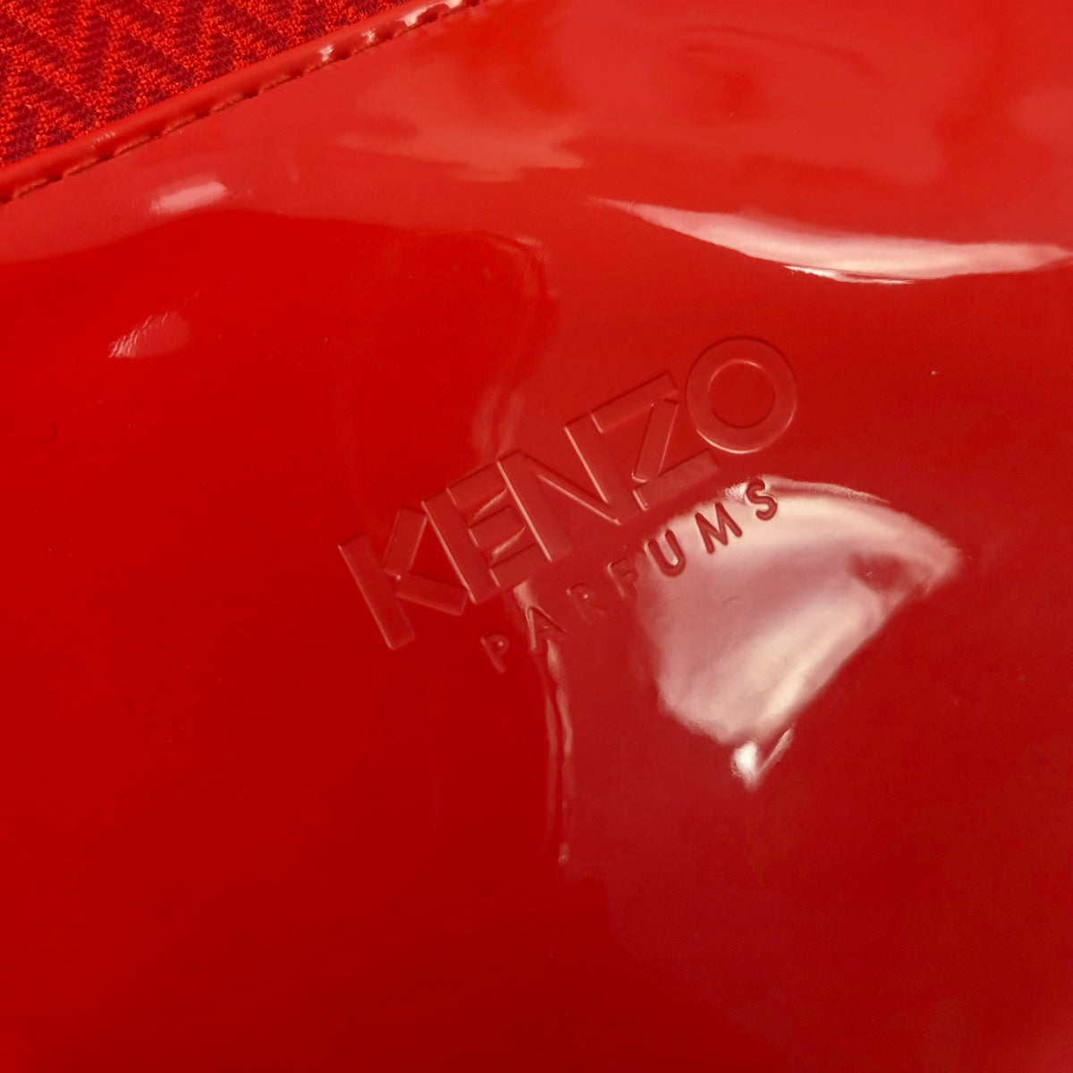 Primo piano del logo Kenzo Parfums impresso a caldo sulla sezione inferiore in vernice.