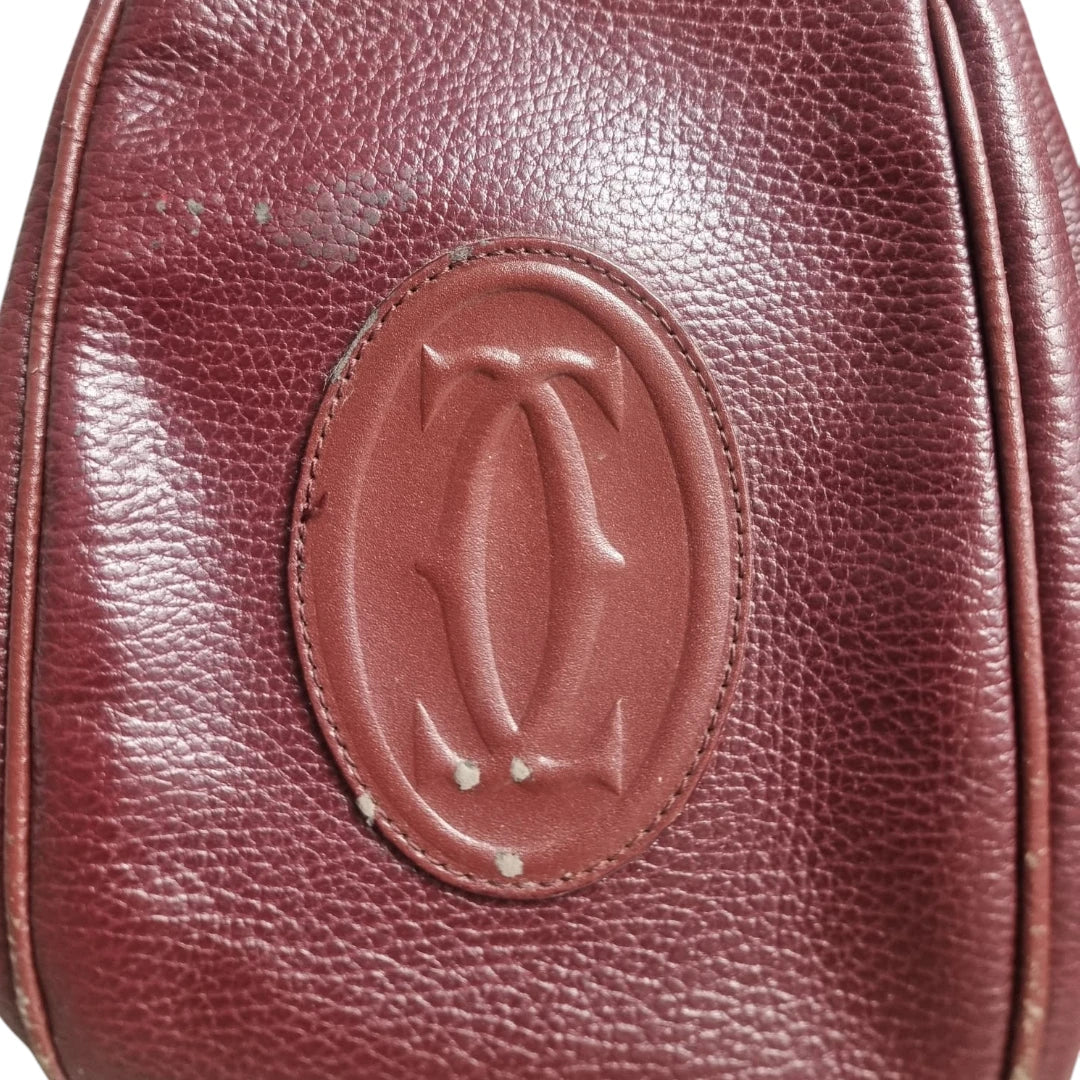 Primo piano del logo ovale Double C impresso su borsa vintage Must de Cartier bordeaux.