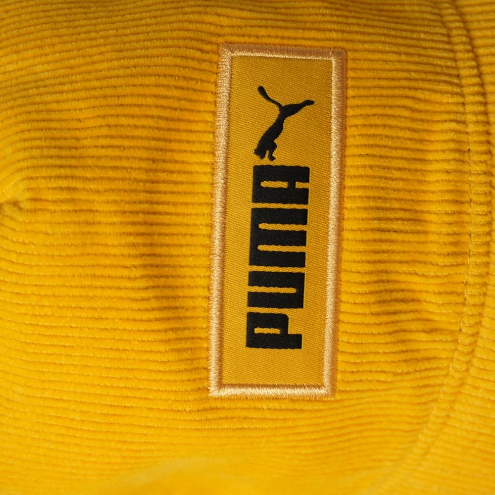 Primo piano del patch rettangolare giallo con logo nero Puma.