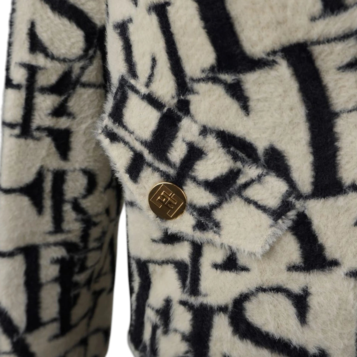 Primo piano sulla trama jacquard logata e bottone dorato piatto.