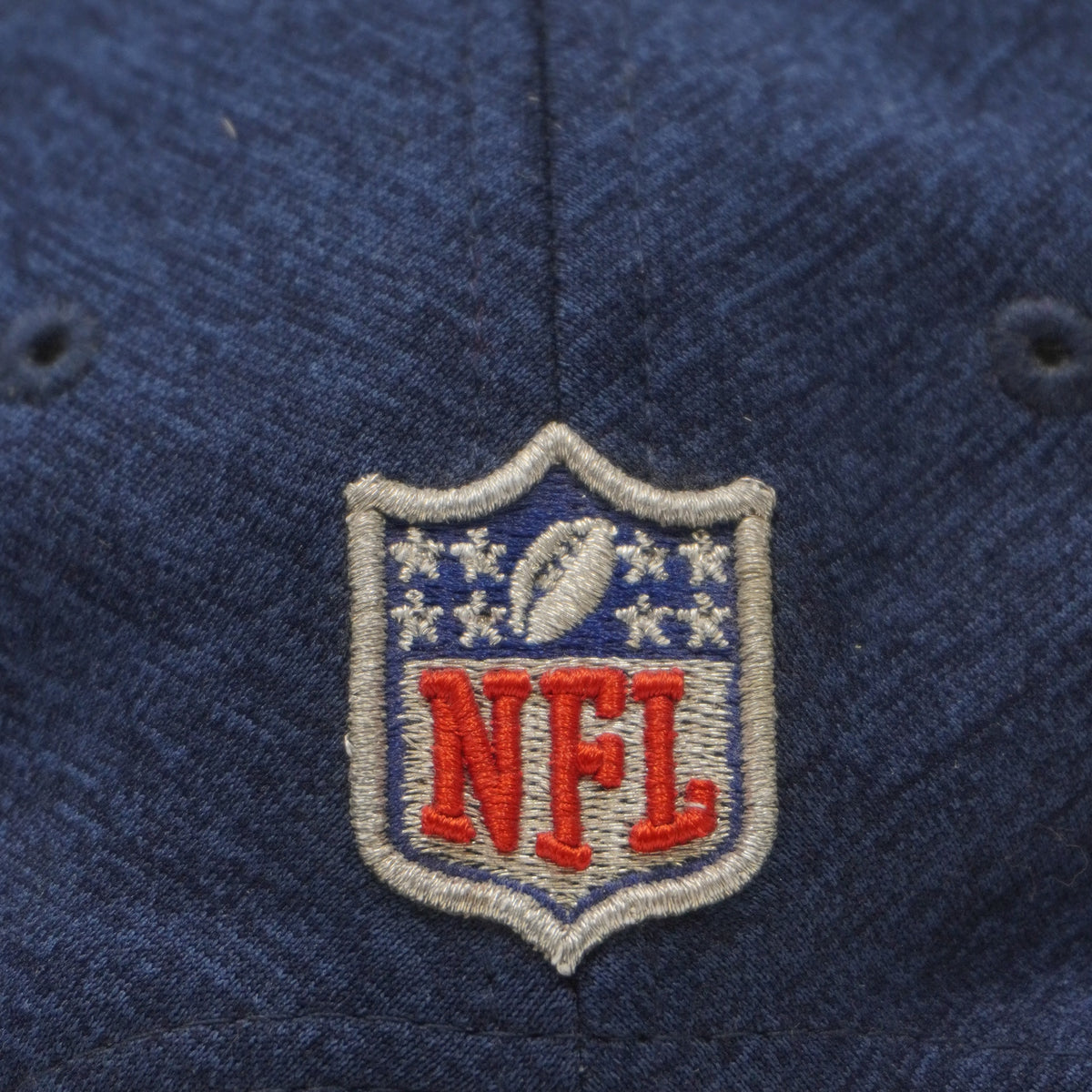 Ricamo ravvicinato dello scudetto ufficiale NFL nei colori blu, bianco e rosso sul tessuto melange.