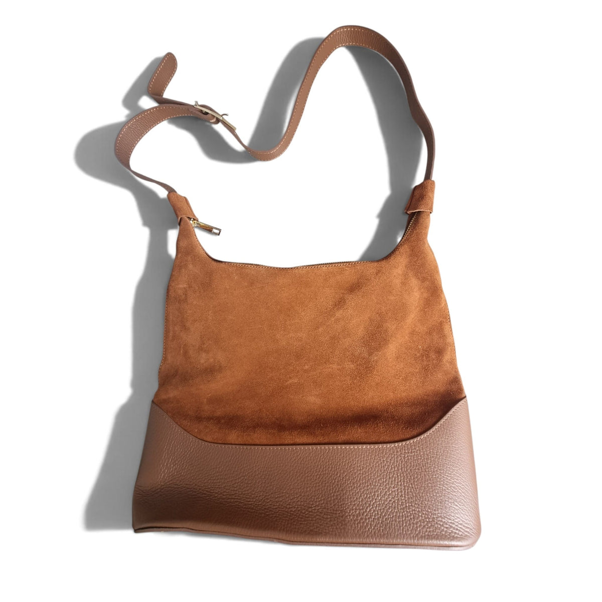 Vista frontale della borsa hobo marrone in camoscio e pelle con ombra proiettata.
