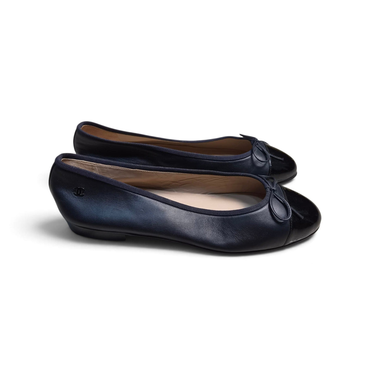 Vista laterale completa della coppia di ballerine Chanel bicolore blu notte e nere su sfondo bianco.