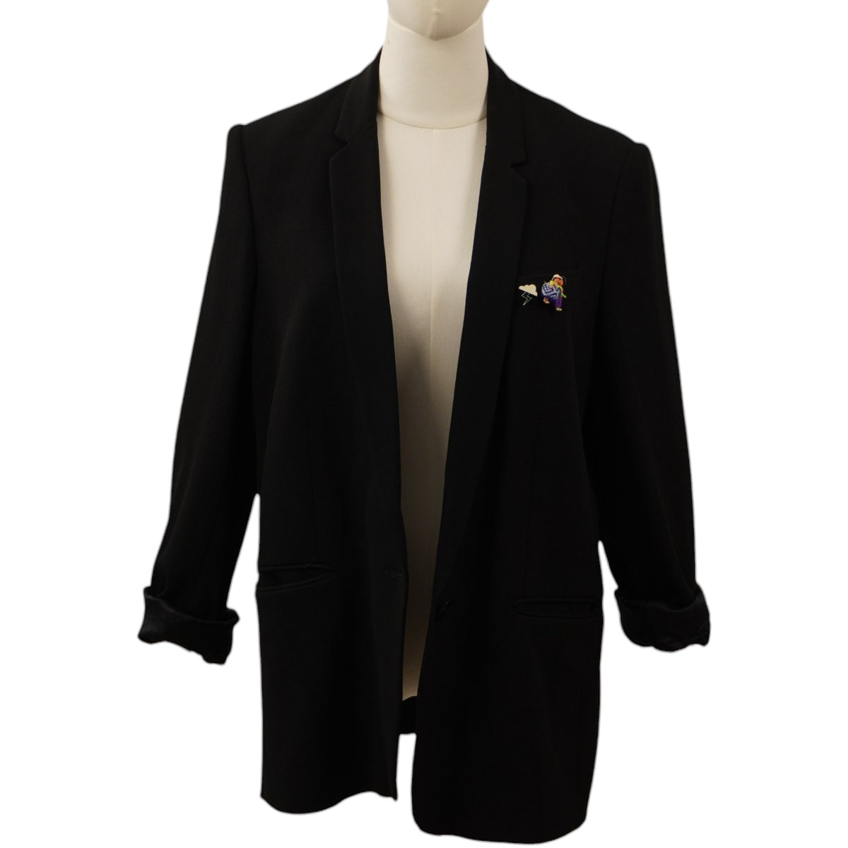 Vista frontale di un blazer nero monopetto Stella McCartney su un manichino, con revers classici e un'applicazione colorata sul taschino frontale.