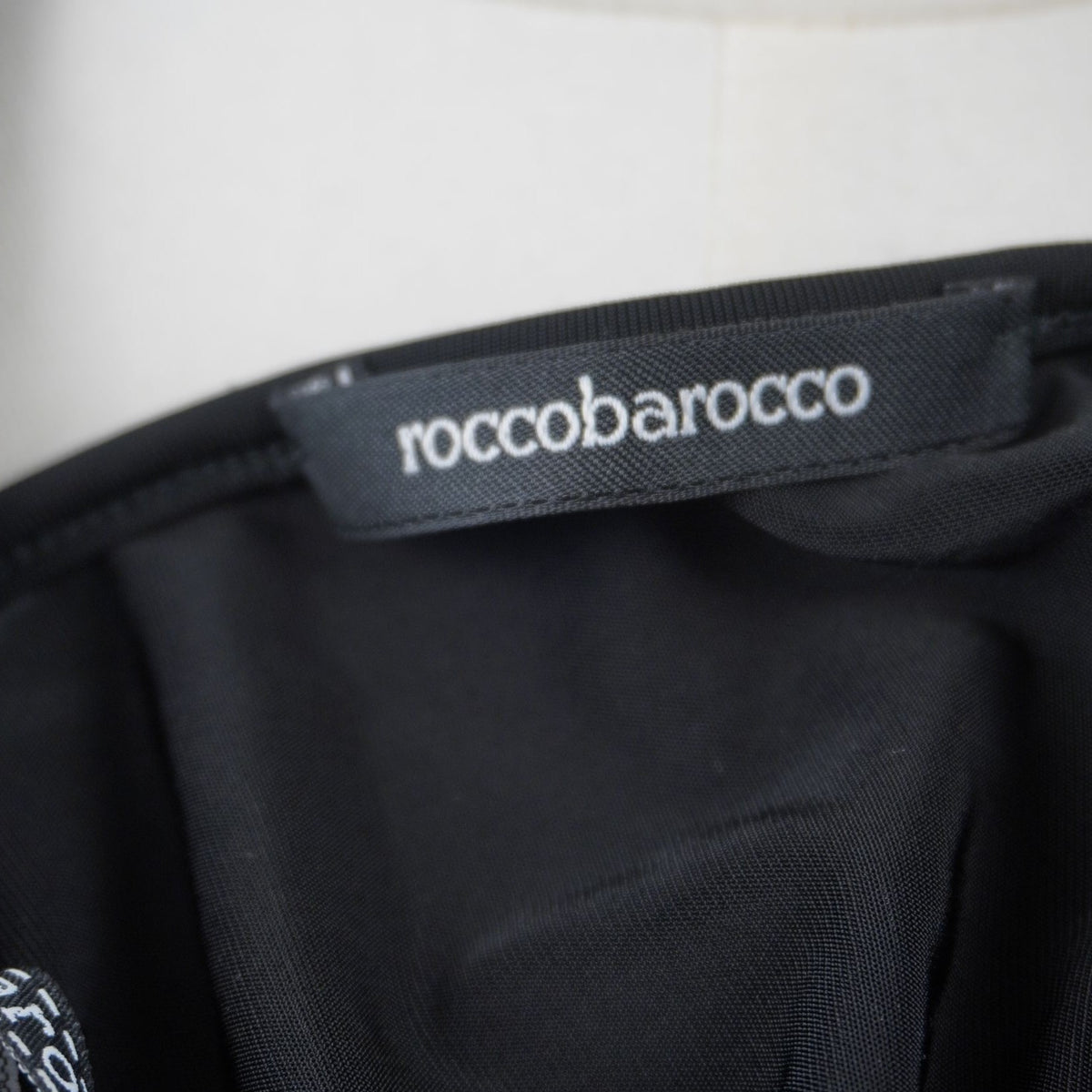 Dettaglio dell'etichetta rettangolare nera con il marchio Roccobarocco cucita sulla finitura interna del bordo.