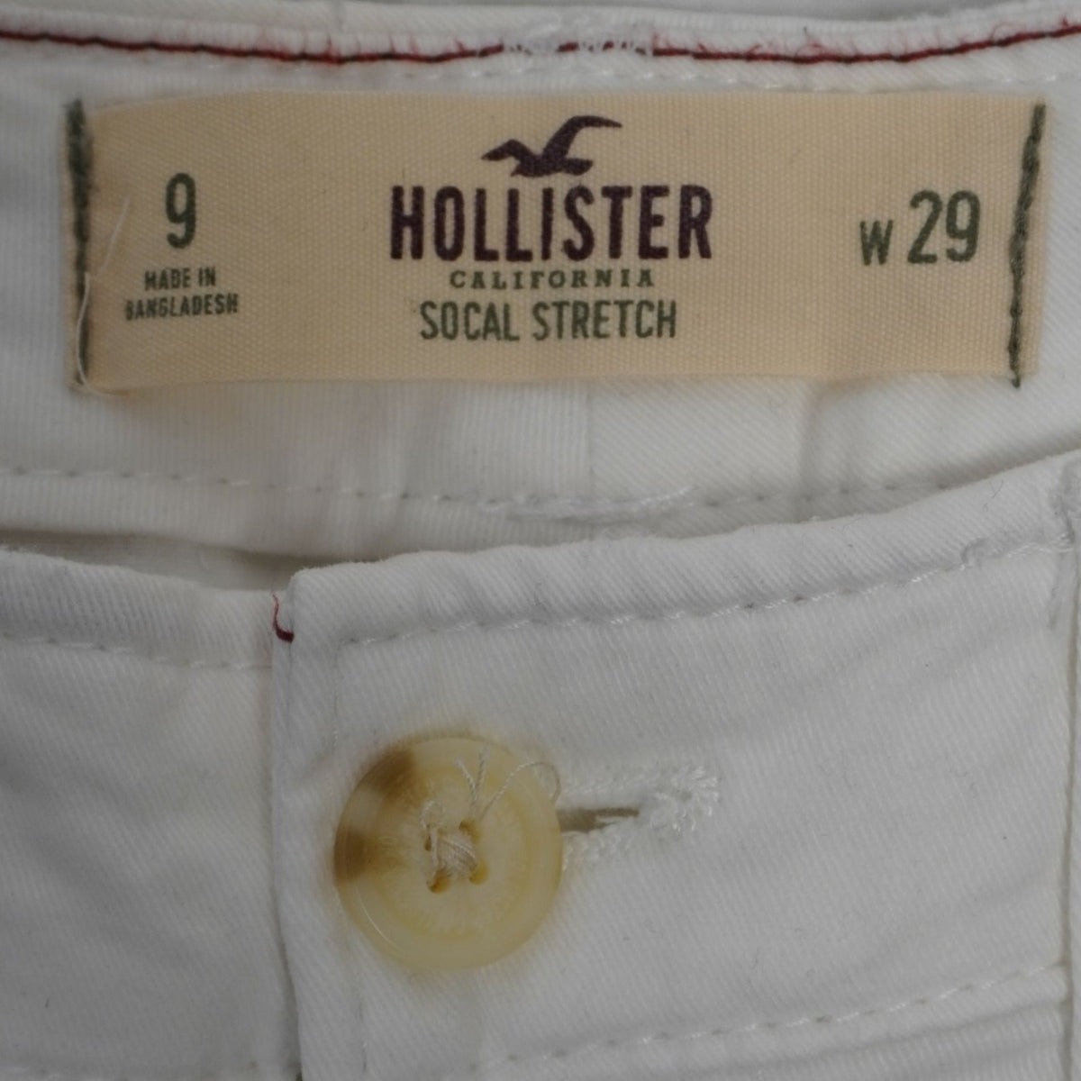 Primo piano dell'etichetta beige Hollister California SoCal Stretch taglia 9 W29 e del bottone frontale biondo.