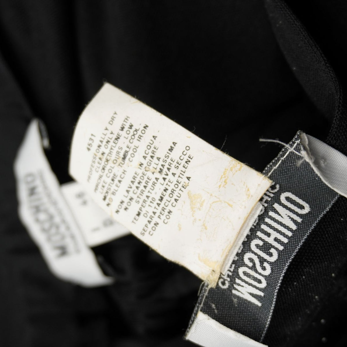 Dettaglio etichetta interna con istruzioni per il lavaggio a secco del completo Moschino.