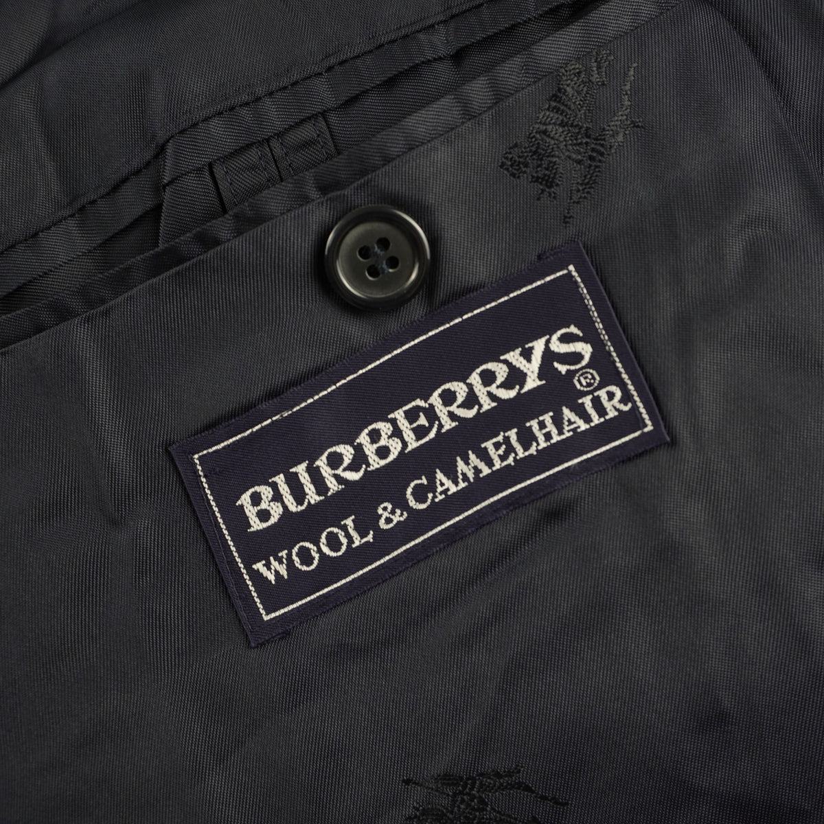 Dettaglio della seconda etichetta in tessuto nero con ricamata la scritta "Burberrys' WOOL & CAMELHAIR" che ne attesta la composizione pregiata.