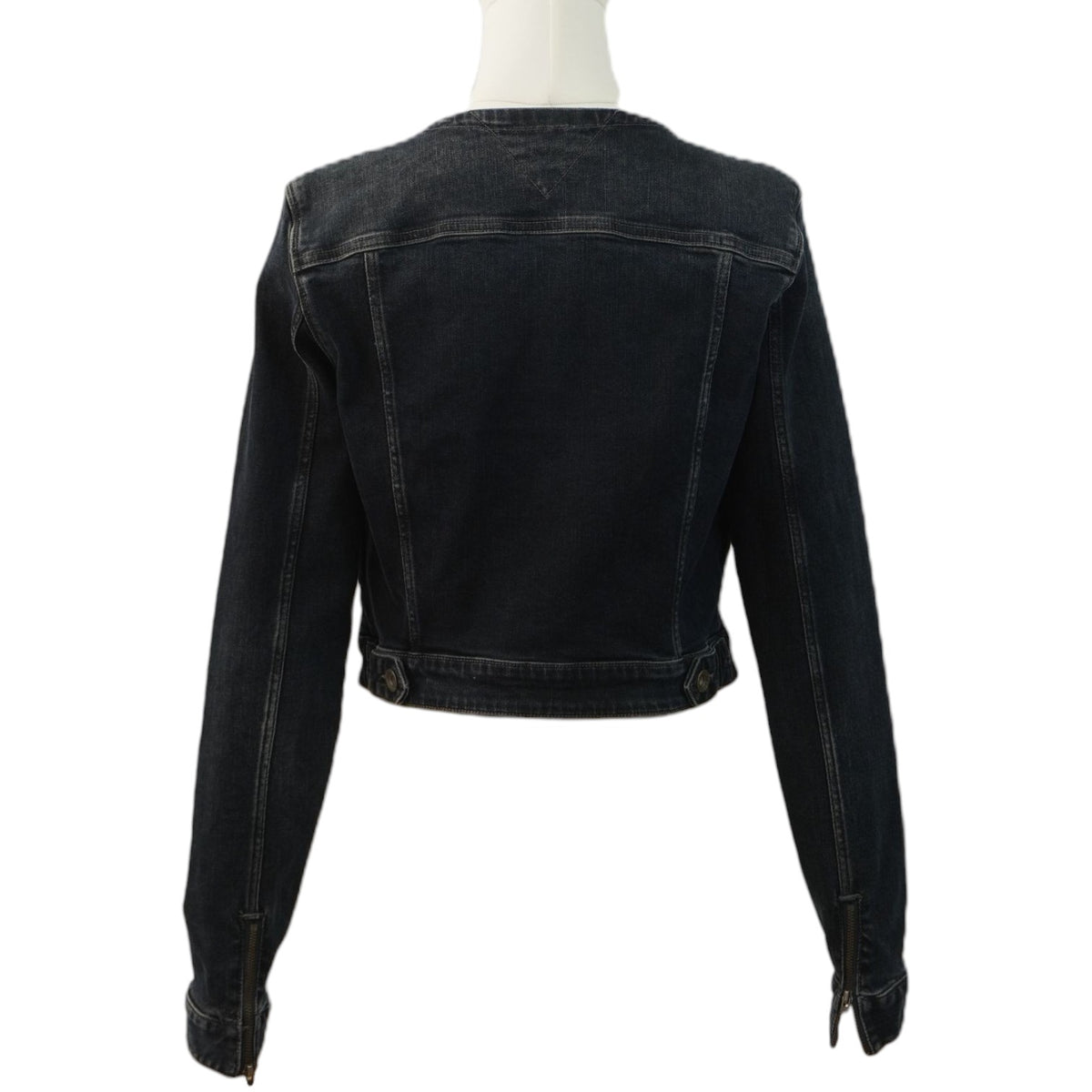  Vista posteriore della giacca di jeans cropped nera sul manichino, che mostra il taglio corto sopra la vita e le cuciture verticali.