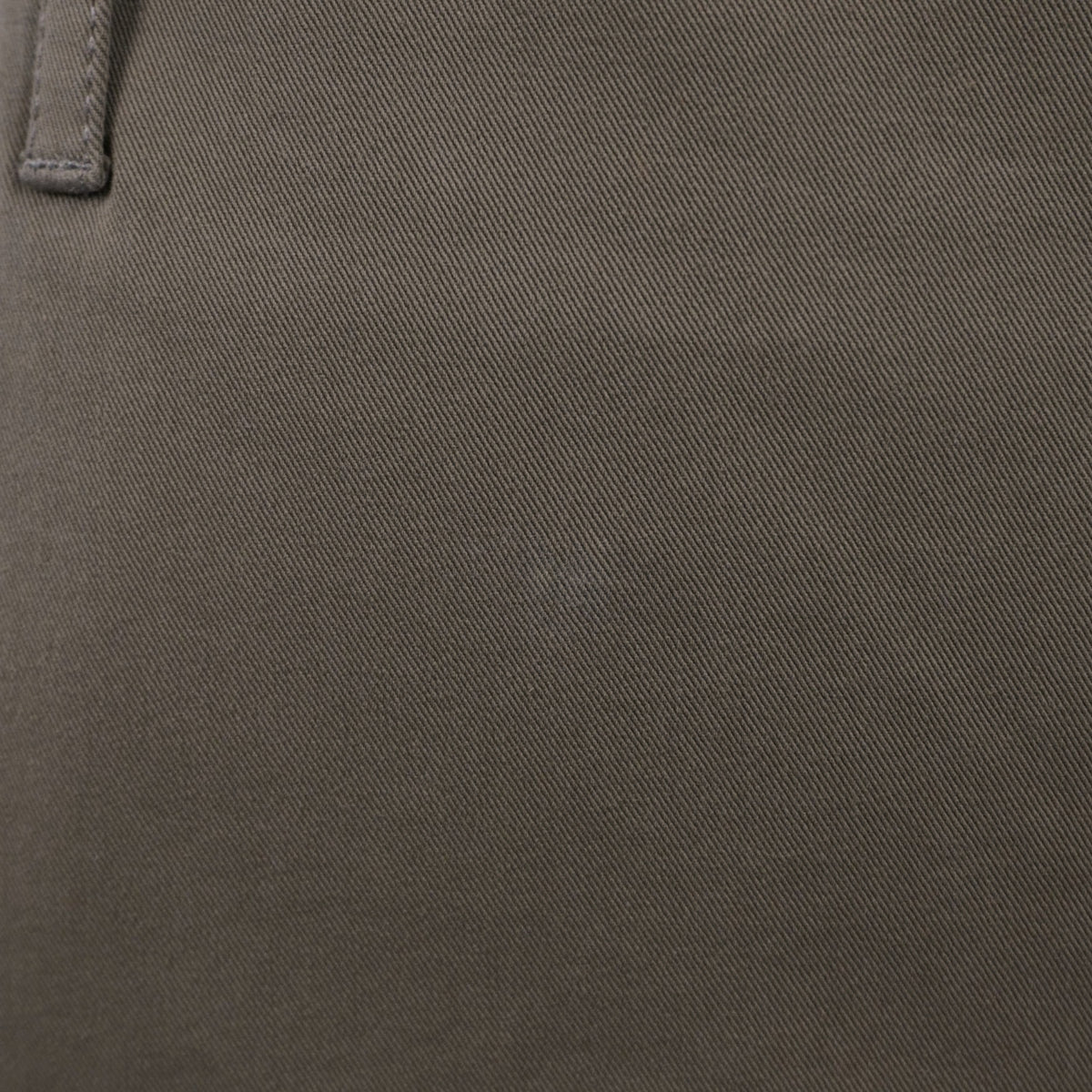 Particolare del tessuto in cotone stretch verde oliva che mostra la trama strutturata ed elasticizzata del capo