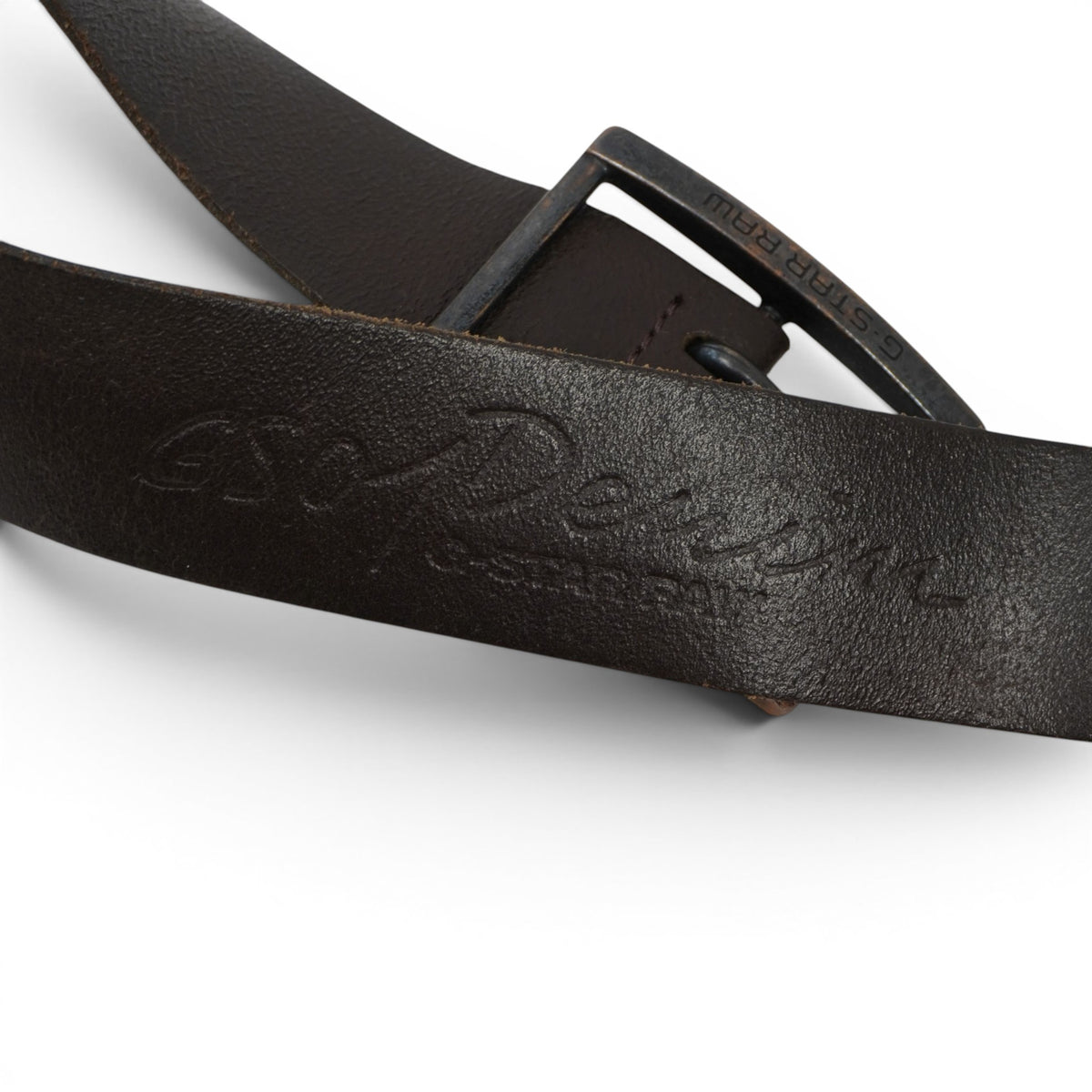 Particolare dell'incisione a caldo con scritta GS-Raw Denim impressa sulla superficie in pelle marrone scuro.