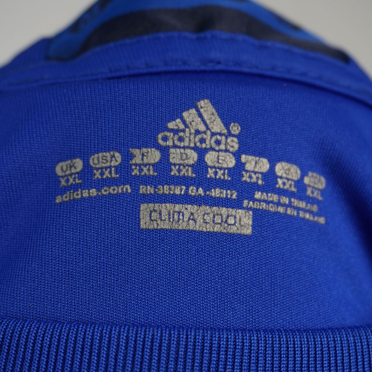 Primo piano della stampa interna al collo con indicazione della taglia XXL e loghi Adidas d'epoca.