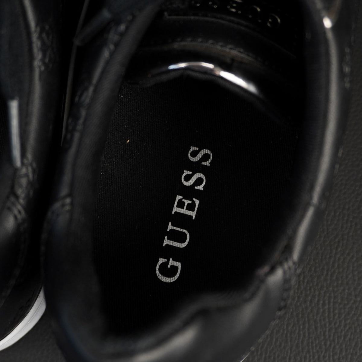 Vista dall'alto dell'interno della sneaker Guess con scritta del brand stampata in argento sulla soletta
