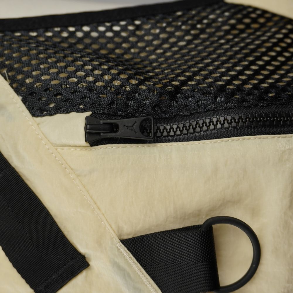 Dettaglio della tasca anteriore in rete nera con zip e anello metallico a D del gilet utility Jordan