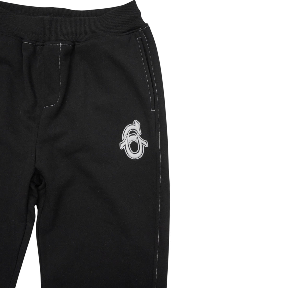 Ingrandimento del logo monogramma bianco ricamato sul davanti dei pantaloni della tuta.